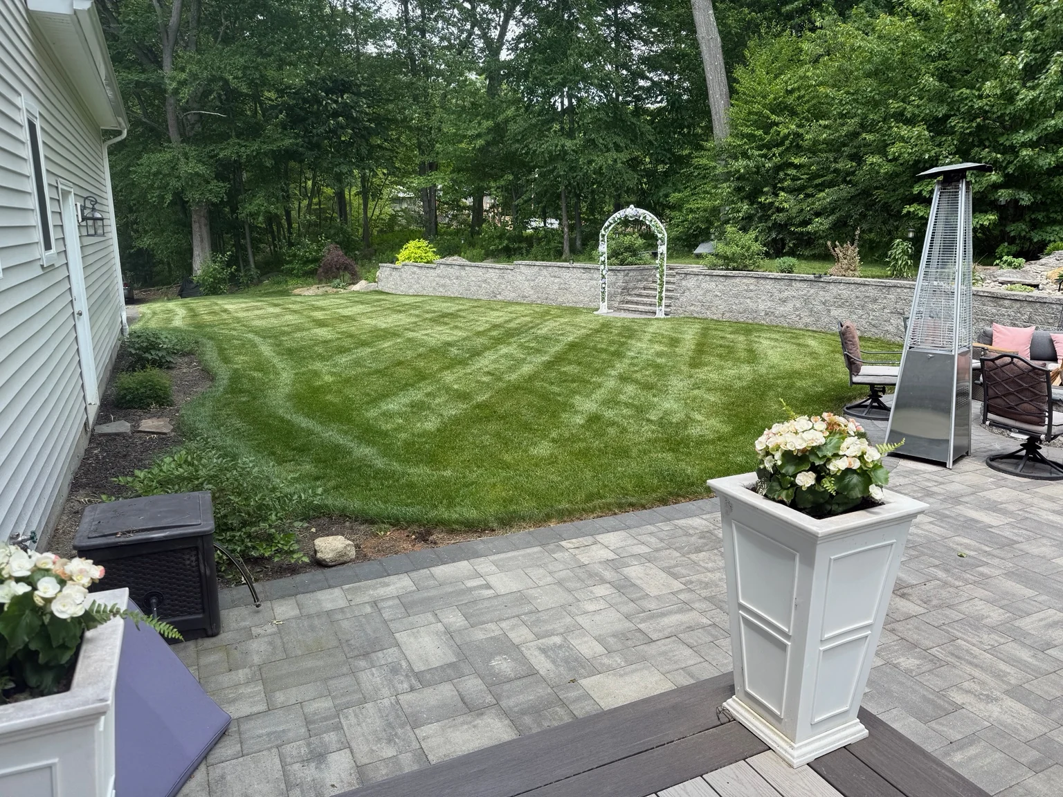 Freshly mowed landscaped backyard beside a patio with visible mowing pattern